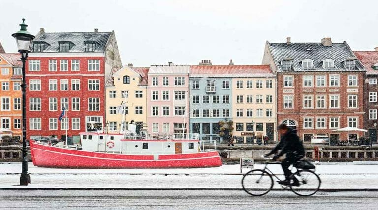 Een fietser langs een boot en gekleurde huizen tijdens een stage in Denemarken