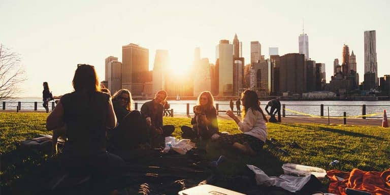 Vrienden die in het park zitten en een picnic hebben bij de ondergaande zon