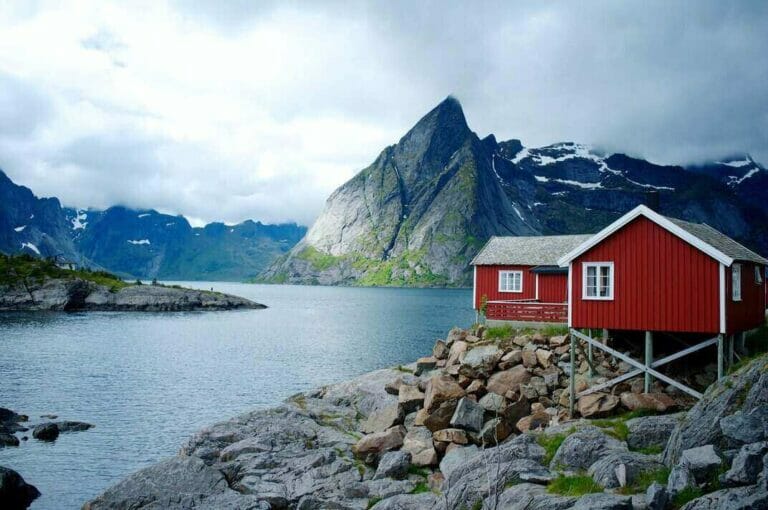 Huisje aan een meer met bergen tijdens een stage in Noorwegen