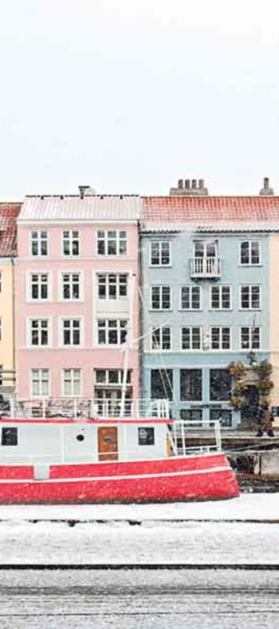 Een fietser langs een boot en gekleurde huizen tijdens een stage in Denemarken
